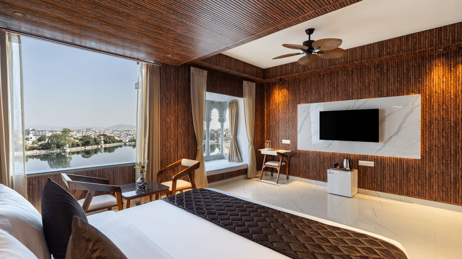 Contemporary hotel bathroom with marbled walls, a standalone wash basin, toilet, and a glass-enclosed shower stall.