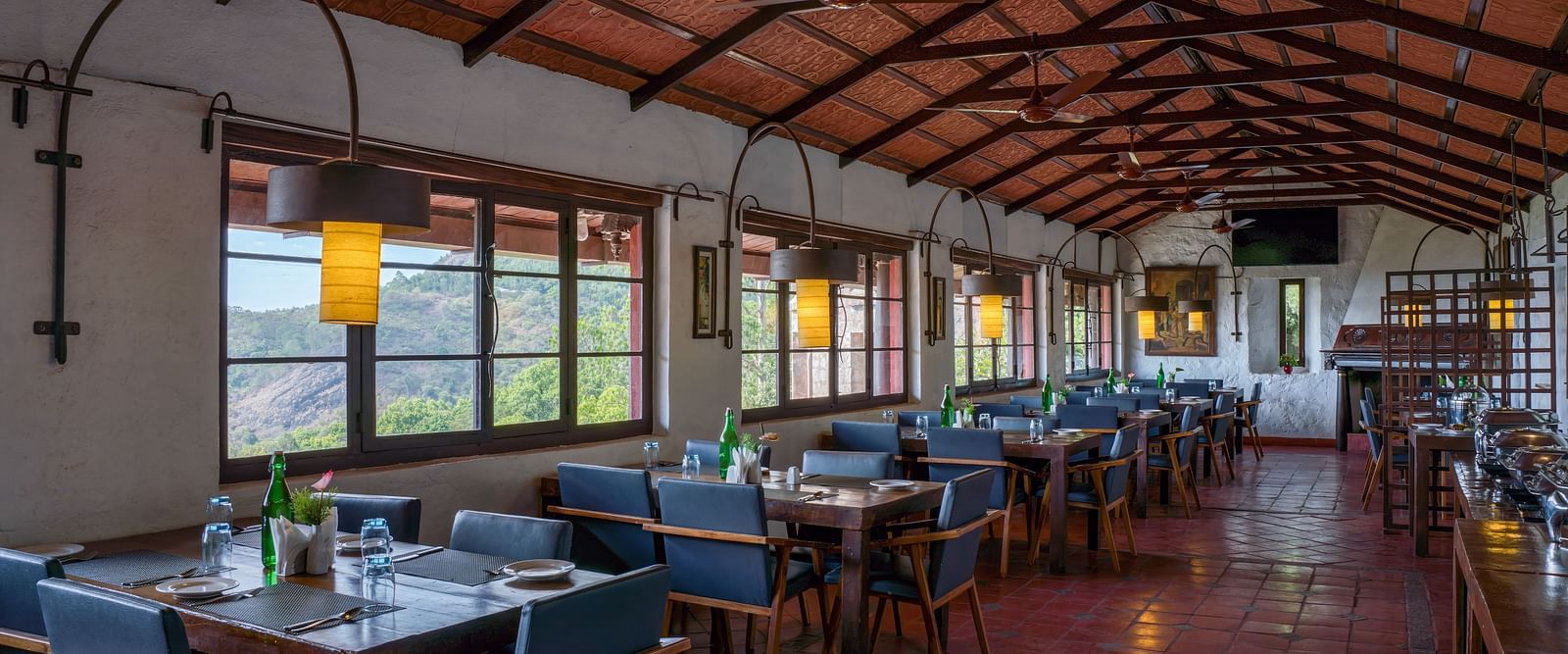 Spacious dining hall with rows of tables and chairs, wooden ceiling, and large windows. | Mango Hill, Yercaud