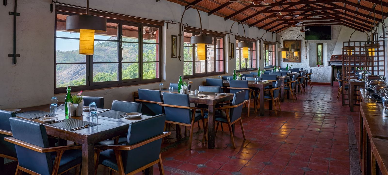 Spacious dining hall with rows of tables and chairs, wooden ceiling, and large windows. | Mango Hill, Yercaud