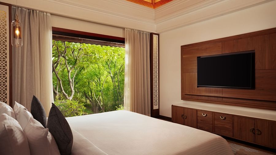 A corner view of the Grand Suite room at The Ananta Udaipur with a king sized bed, a balcony with the jungle view.