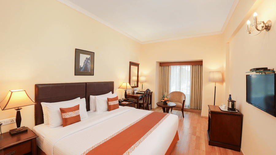 A room with a large bed, spreads, pillows, chairs, and a door. | MGM Mark Whitefield