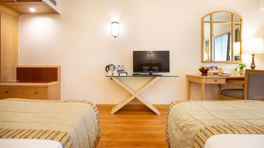 room with twin beds, a television and modern wooden flooring
