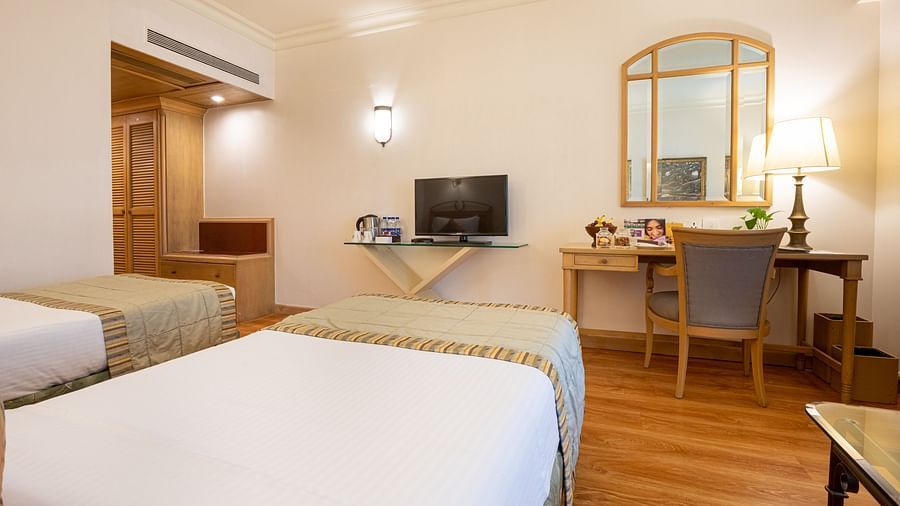 room with twin beds, a television and modern wooden flooring
