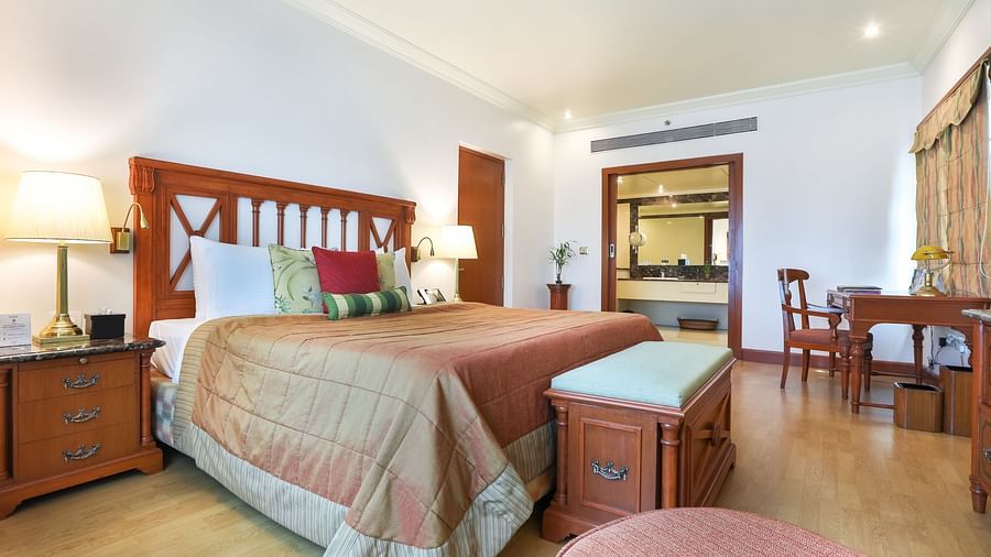 cosy bedroom with a king size bed and wooden flooring - The Orchid Hotel Mumbai Vile Parle