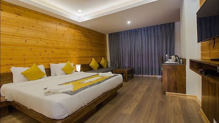 An image of a premium room with a bed, a couch, a table, and room amenities - Yashshree Sanderling, Darjeeling