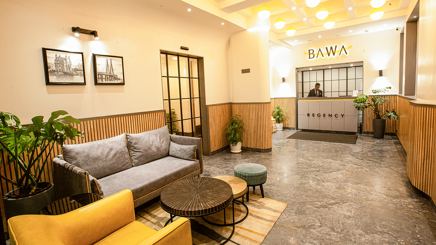 A corner view of the lobby at Hotel Bawa Regency, Dadar, featuring indoor plants and a comfy sofa.