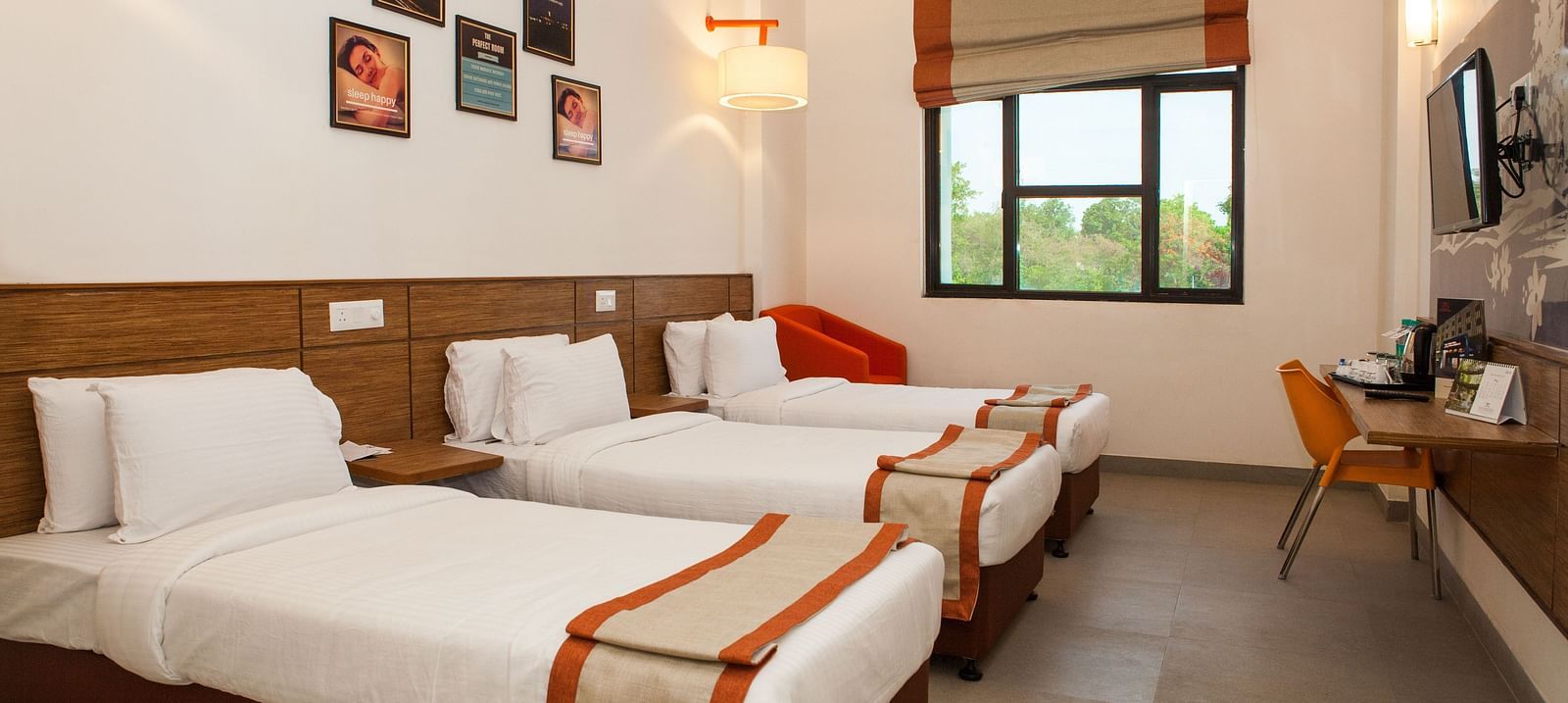 a room with three single beds and a window at the far end of the room - Max Hotel Jabalpur