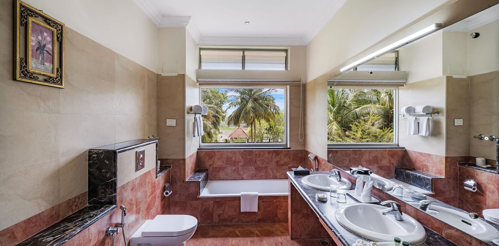 An image of a washroom with toiletries, and bath tub with views of the serene landscape - GReaT Trails River View Resort Thanjavur By GRT Hotels