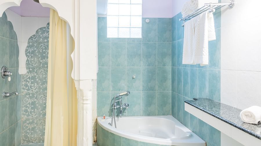 A small bathtub in the corner next to a shower area in the bathroom inside inside Standard rooms - Mandawa Haveli, Jaipur