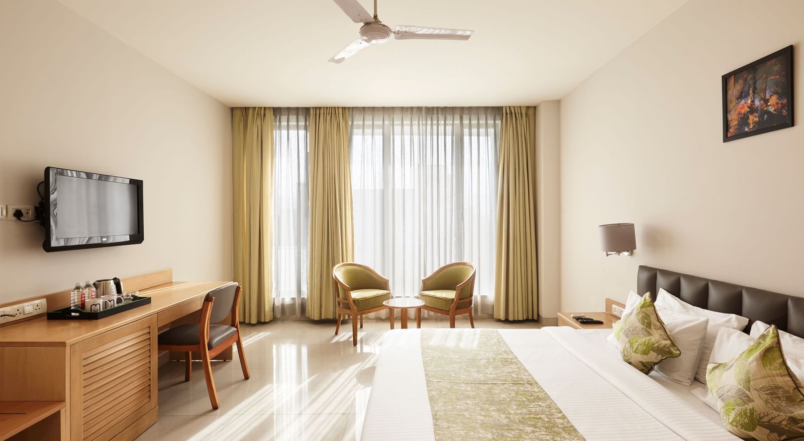 A wide-angle view of a modern hotel room at Monday Hotels Mahape, Navi Mumbai, with the bed and a view into the bathroom.