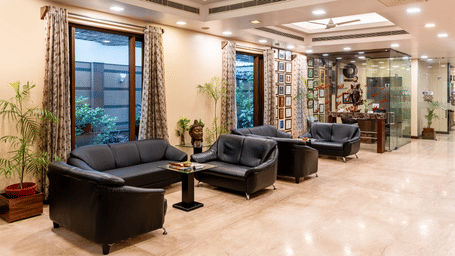 Spacious hotel lobby and reception area with comfortable black leather sofas, polished floors, and large windows offering plenty of natural light - Amantra Comfort Hotel