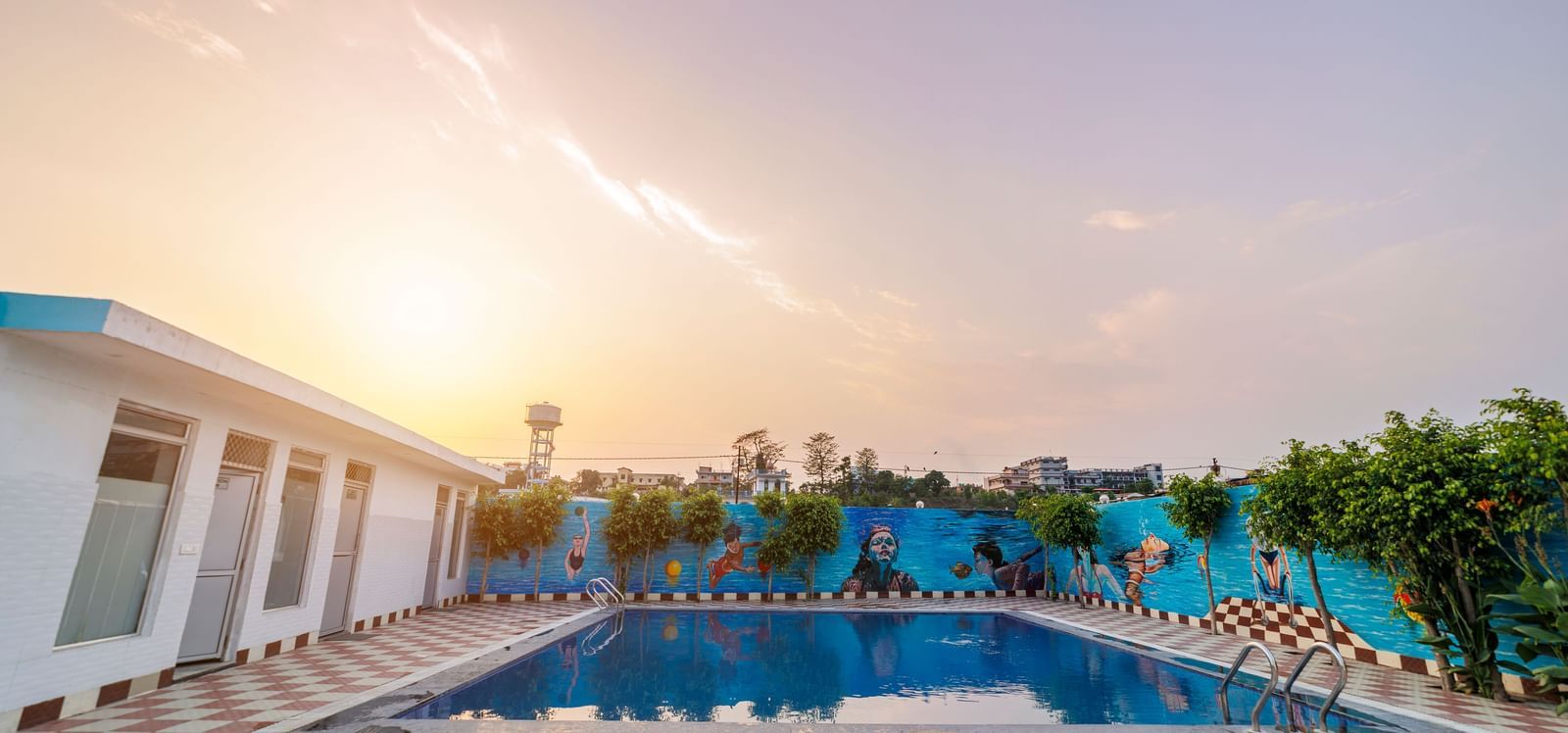 Swimming pool at Inde Reva Resorts Rishhikesh surrounded by poolside seating and tiled deck at sunset.