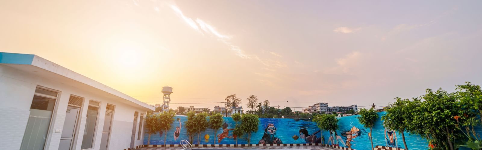 Swimming pool at Inde Reva Resorts Rishhikesh surrounded by poolside seating and tiled deck at sunset.