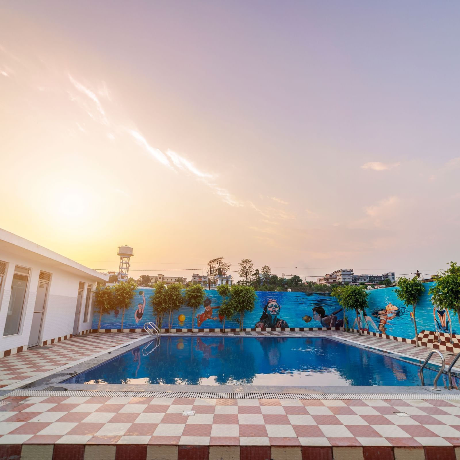 Swimming pool at Inde Reva Resorts Rishhikesh surrounded by poolside seating and tiled deck at sunset.