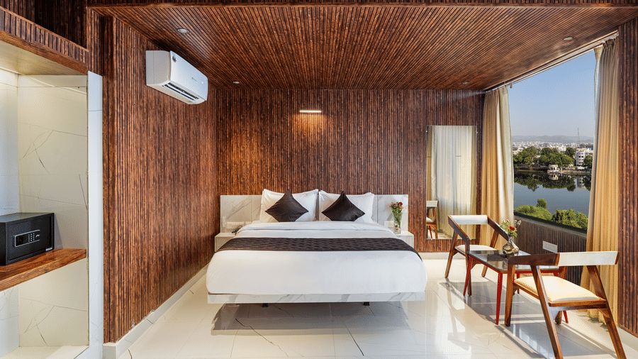 Hotel bedroom interior featuring a large bed, wooden cladding, a flat-screen TV, and an entrance to a separate area.