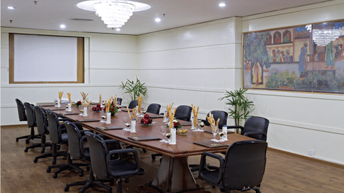 A professional conference room with a long table, executive chairs, and a projector screen ready for a business meeting - Clarks Avadh, Lucknow