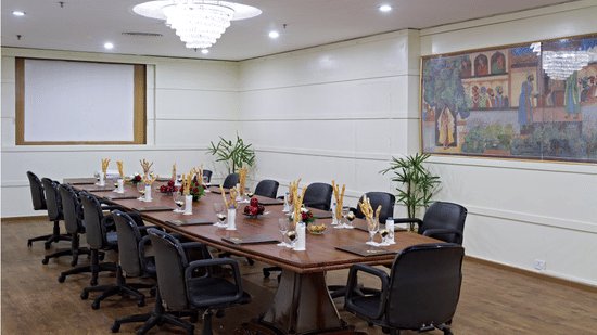 A professional conference room with a long table, executive chairs, and a projector screen ready for a business meeting - Clarks Avadh, Lucknow