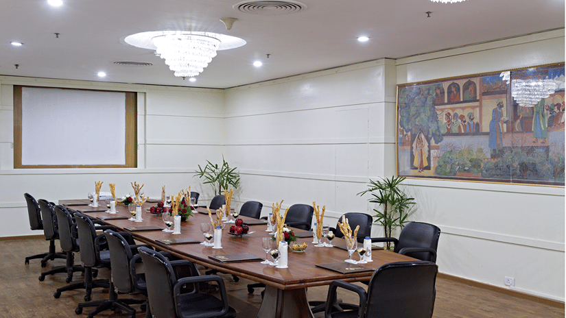 A professional conference room with a long table, executive chairs, and a projector screen ready for a business meeting - Clarks Avadh, Lucknow