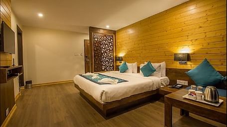 An image of an executive premium room showcasing the room amenities such as tea and coffee maker, flat screen TV, bed, bed side tables, and lamps - Yashshree Sanderling, Darjeeling