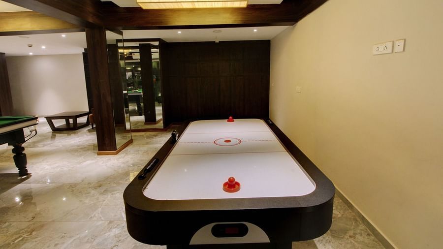 An air hockey table in a well-lit room with wooden accents and reflective marble flooring, providing an indoor gaming experience