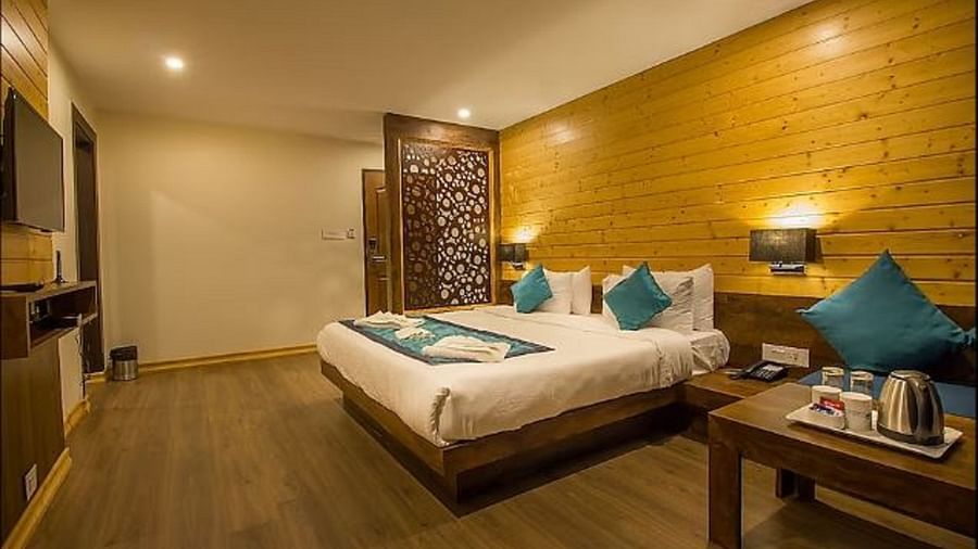 An image of an executive premium room showcasing the room amenities such as tea and coffee maker, flat screen TV, bed, bed side tables, and lamps - Yashshree Sanderling, Darjeeling