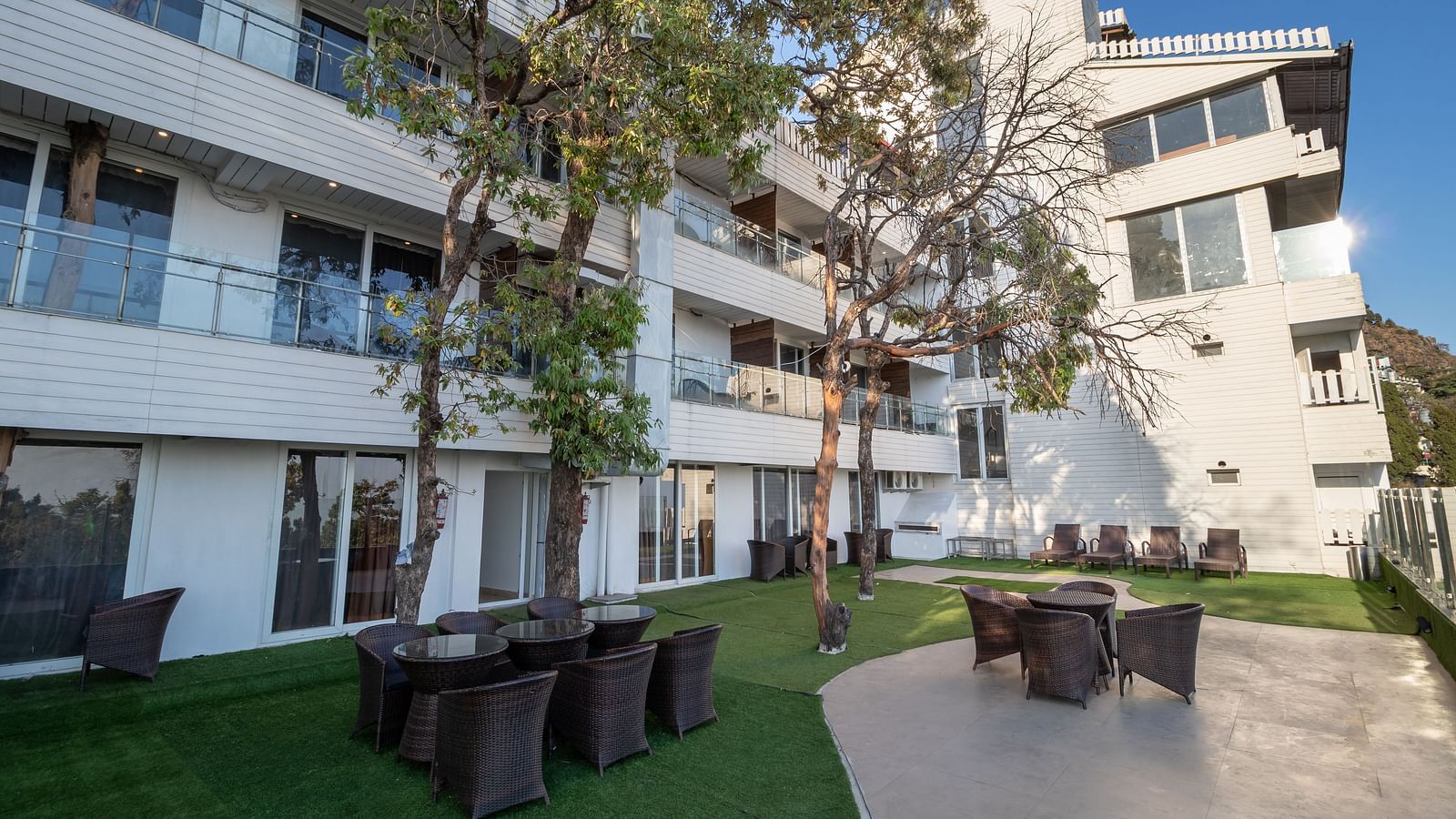 A facade image of Yashshree, Mussoorie with outdoor seating arrangement and greenery