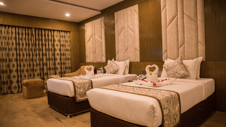 A twin-bedded hotel room at Benzz Park Chennai with elegant headboards, soft lighting, and modern furnishings.