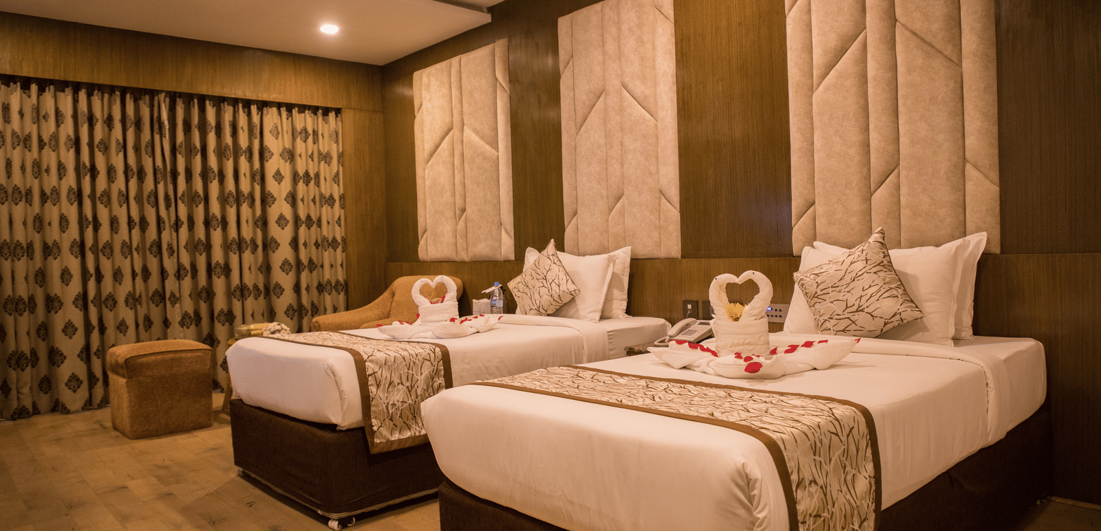 A twin-bedded hotel room at Benzz Park Chennai with elegant headboards, soft lighting, and modern furnishings.