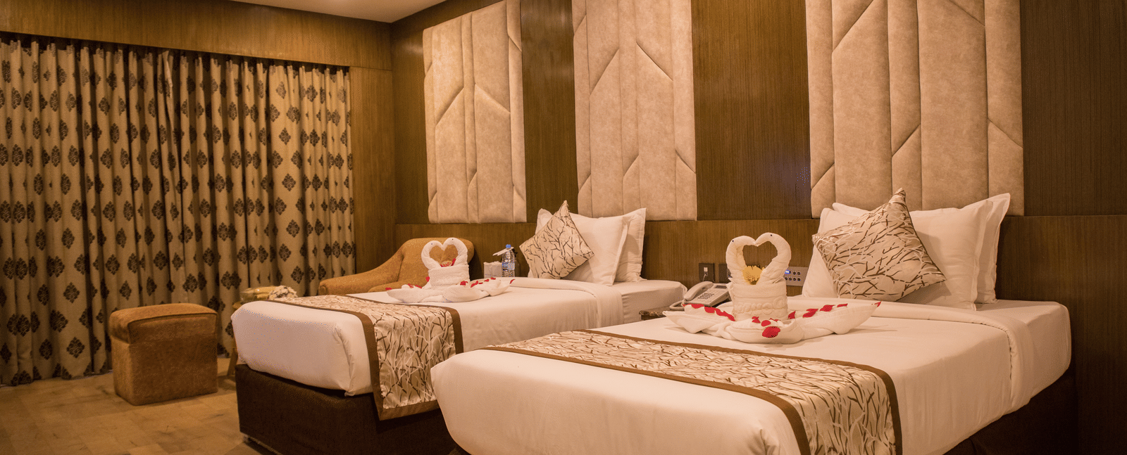 A twin-bedded hotel room at Benzz Park Chennai with elegant headboards, soft lighting, and modern furnishings.