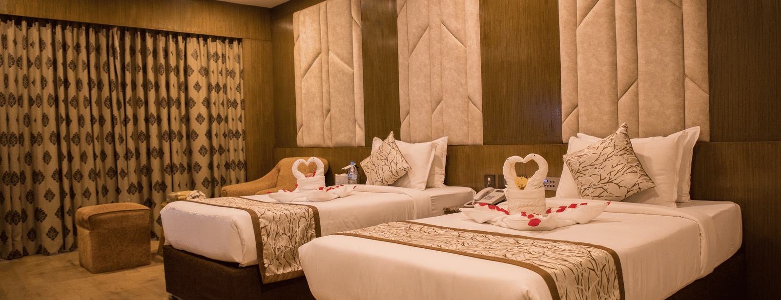 A twin-bedded hotel room at Benzz Park Chennai with elegant headboards, soft lighting, and modern furnishings.