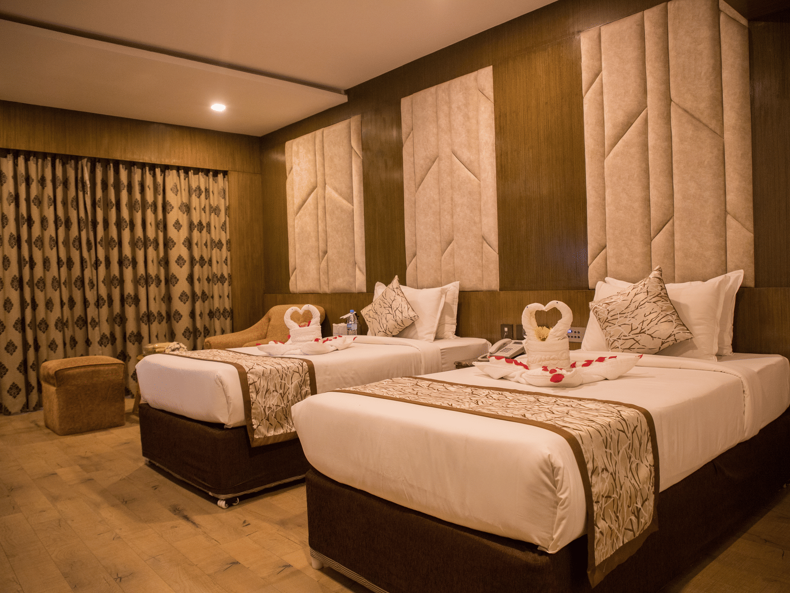 A twin-bedded hotel room at Benzz Park Chennai with elegant headboards, soft lighting, and modern furnishings.