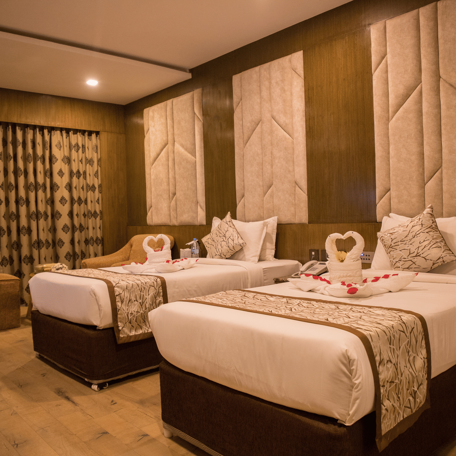 A twin-bedded hotel room at Benzz Park Chennai with elegant headboards, soft lighting, and modern furnishings.