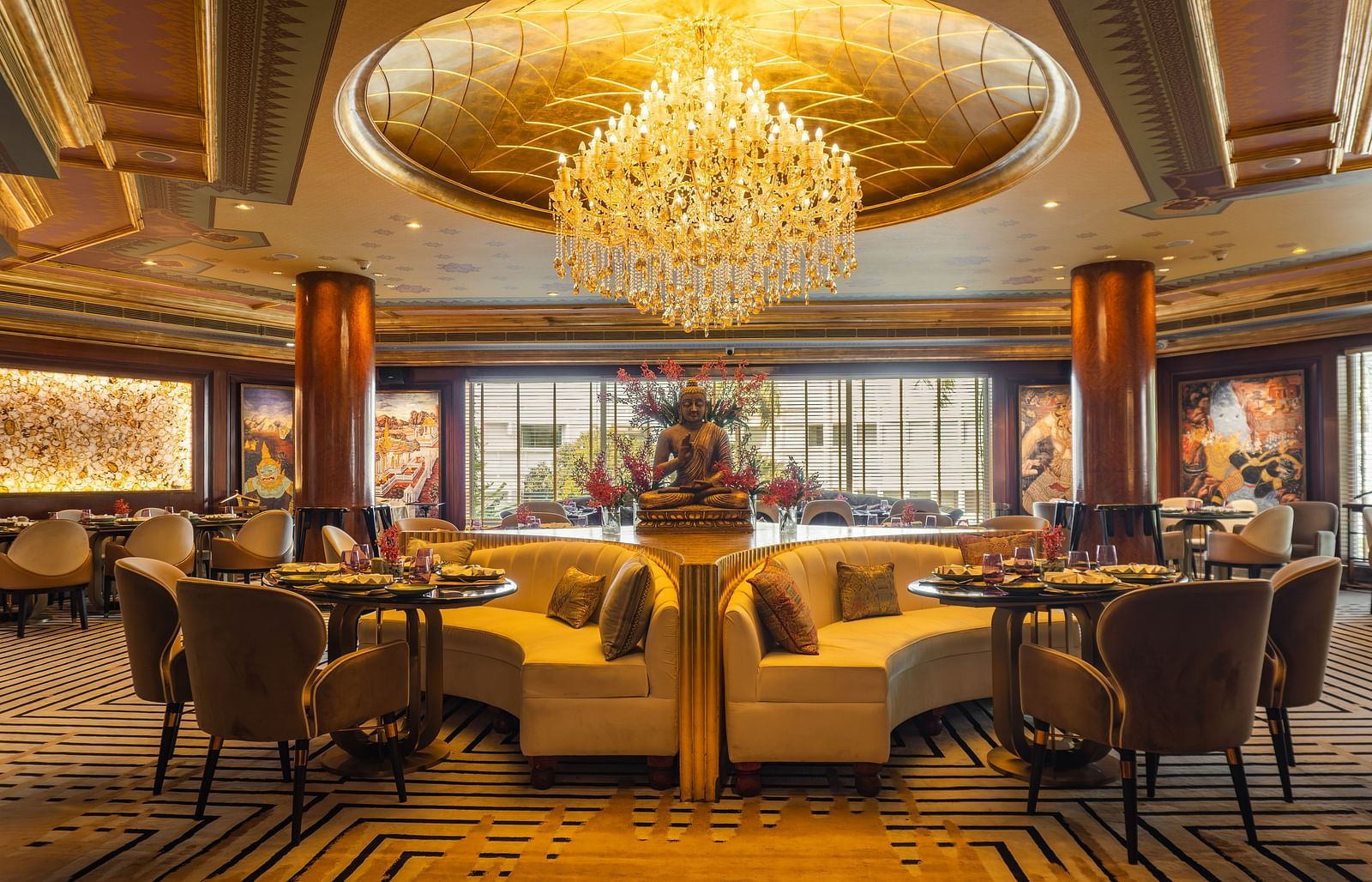Erawaan dining at The Claridges New Delhi, featuring a chandelier, cosy sofas, and a serene Buddha statue centerpiece