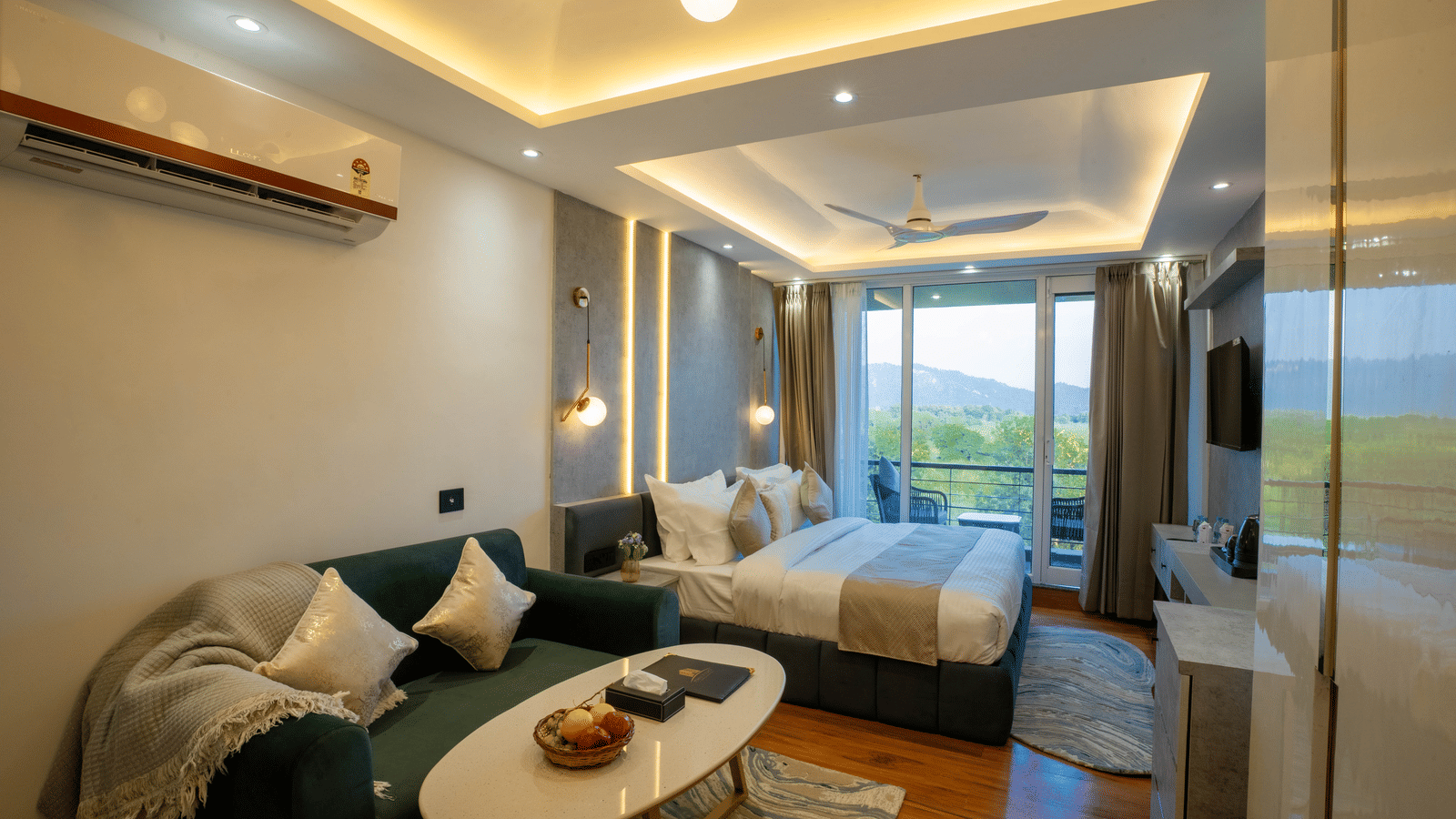 A guest room at Sukoon by the Ganges featuring a comfortable sofa and coffee table in the foreground, facing the bed and balcony.