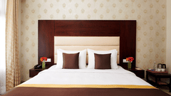 straight on view of a double bed and a nightstand in the DELUXE ROOM - Royal Kingdom Sarovar Portico, Pilibhit