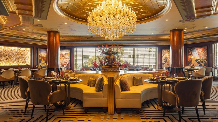 Erawaan dining at The Claridges New Delhi, featuring a chandelier, cosy sofas, and a serene Buddha statue centerpiece