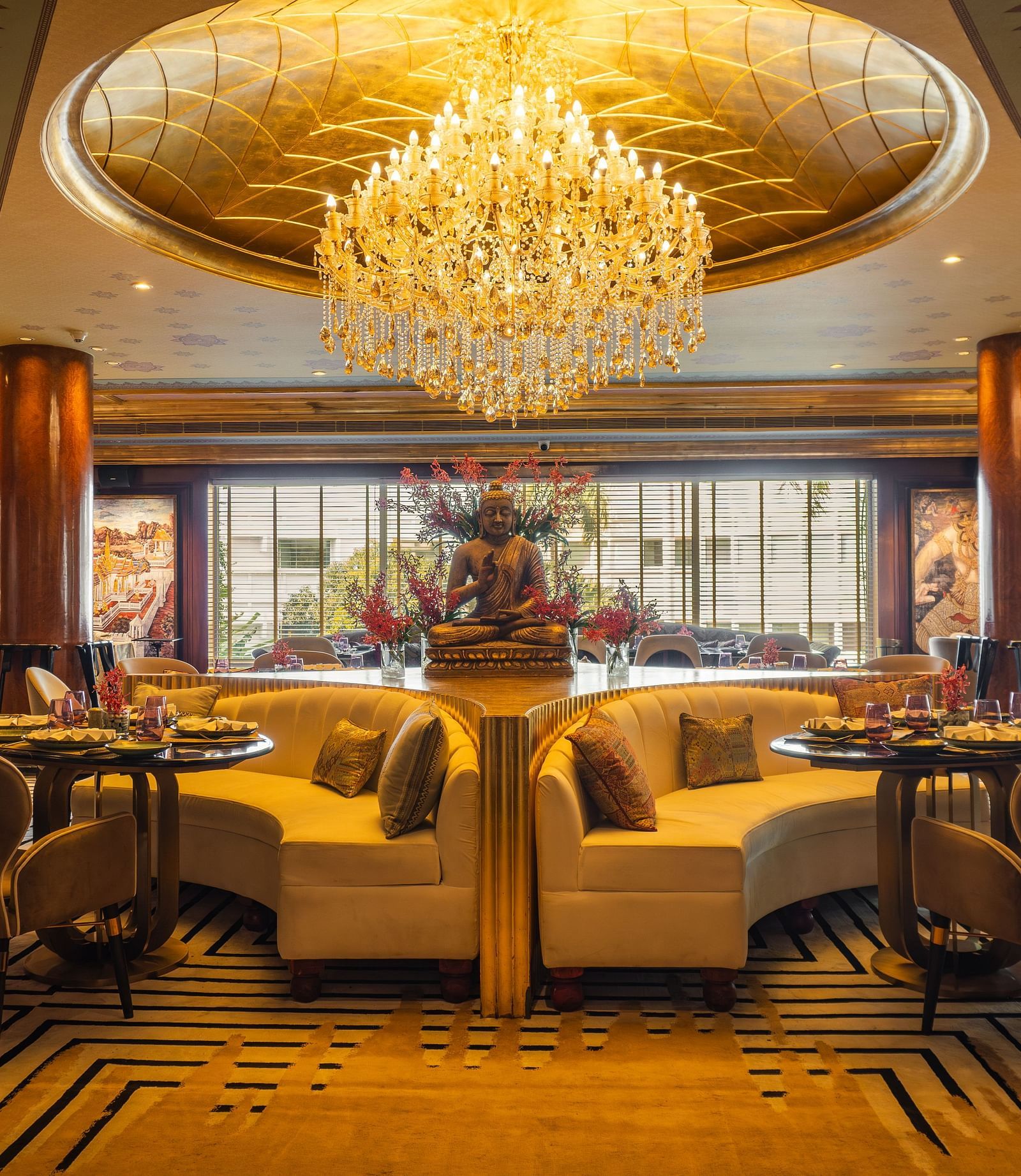Erawaan dining at The Claridges New Delhi, featuring a chandelier, cosy sofas, and a serene Buddha statue centerpiece