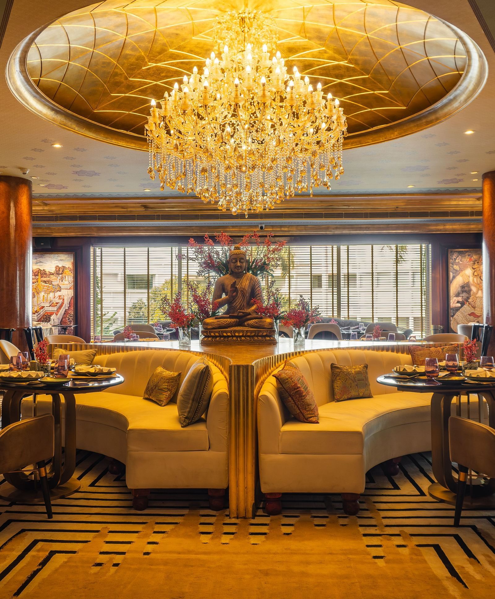 Erawaan dining at The Claridges New Delhi, featuring a chandelier, cosy sofas, and a serene Buddha statue centerpiece