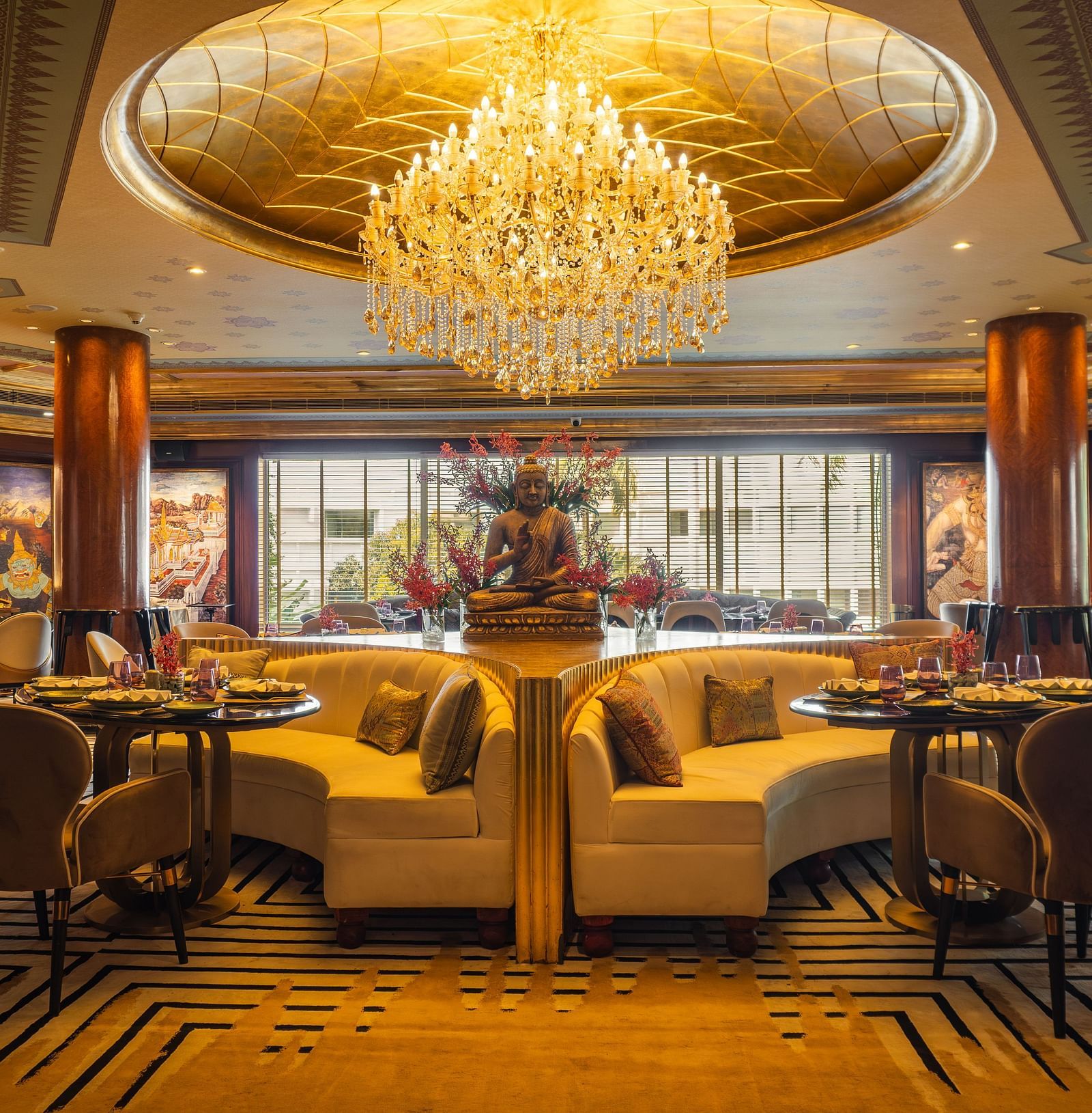 Erawaan dining at The Claridges New Delhi, featuring a chandelier, cosy sofas, and a serene Buddha statue centerpiece