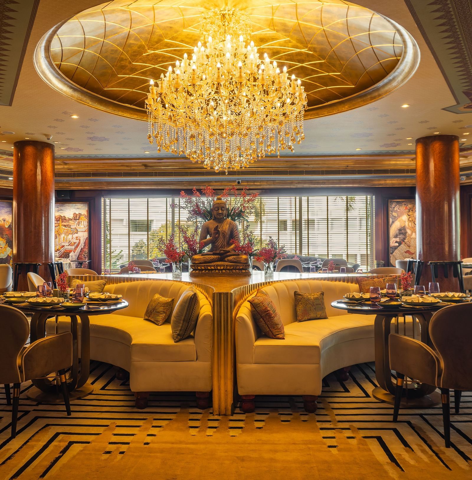 Erawaan dining at The Claridges New Delhi, featuring a chandelier, cosy sofas, and a serene Buddha statue centerpiece