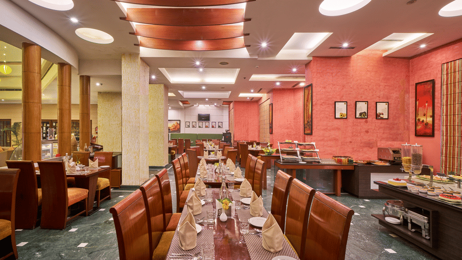 Interior dining area at HHI Varanasi featuring elegant seating, buffet setup, warm lighting, and a spacious restaurant ambiance.