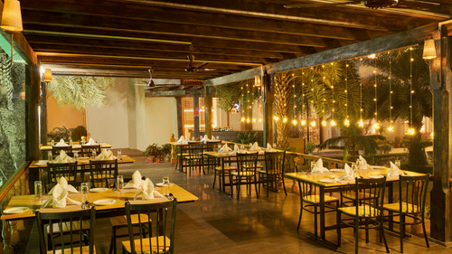 tables set up for service beside fairy lights hanging from the wall of our restaurant - Royal Kingdom Sarovar Portico, Pilibhit