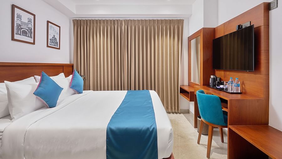 Deluxe room of our hotel with a king size bed, television, table and chair.