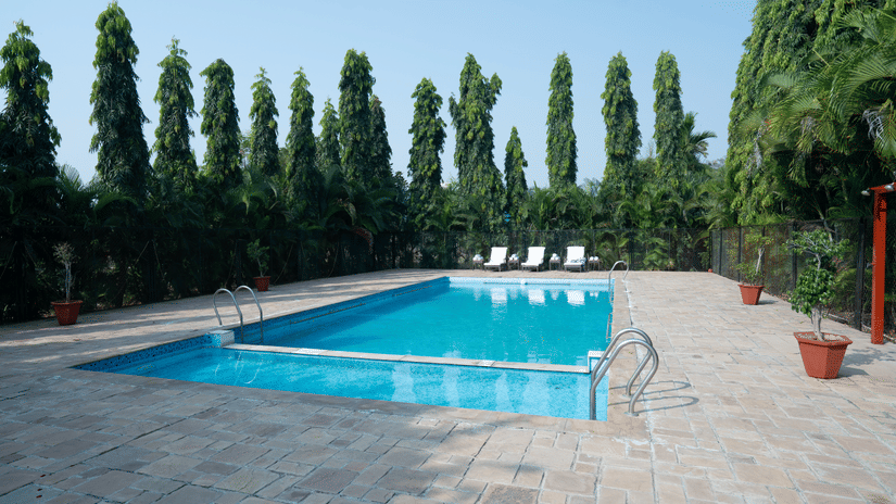 Outdoor swimming pool surrounded by greenery at Pride Elite Phaltan.