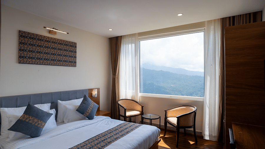 A side view of bed in a room with a huge window that offers mountain views | Voyage The Royal Retreat, Gangtok