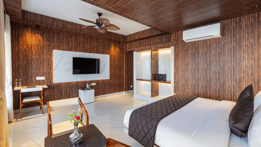 Boutique hotel room with a quilted bedspread, a ceiling fan, timber wall panels, and a window with a lake view.