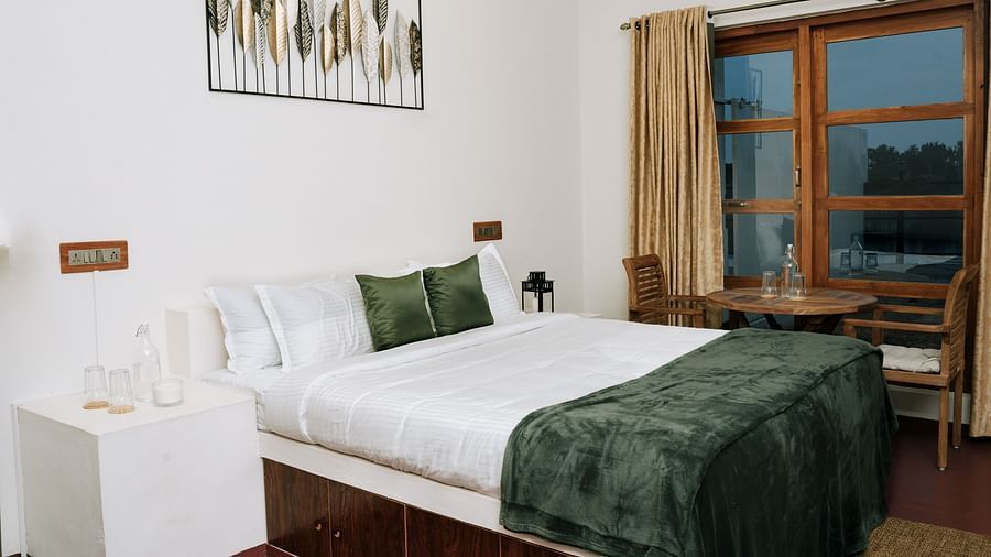 A bed in a room that has a glass window | Habba Dates Villa, Hampasandra