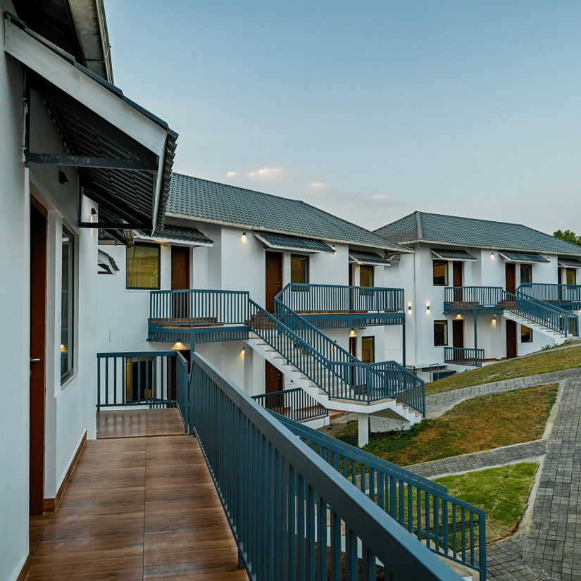 An outdoor walkway and staircase of a hotel building with railings overlooking a grassy area | Abad Silvermist, Vagamon
