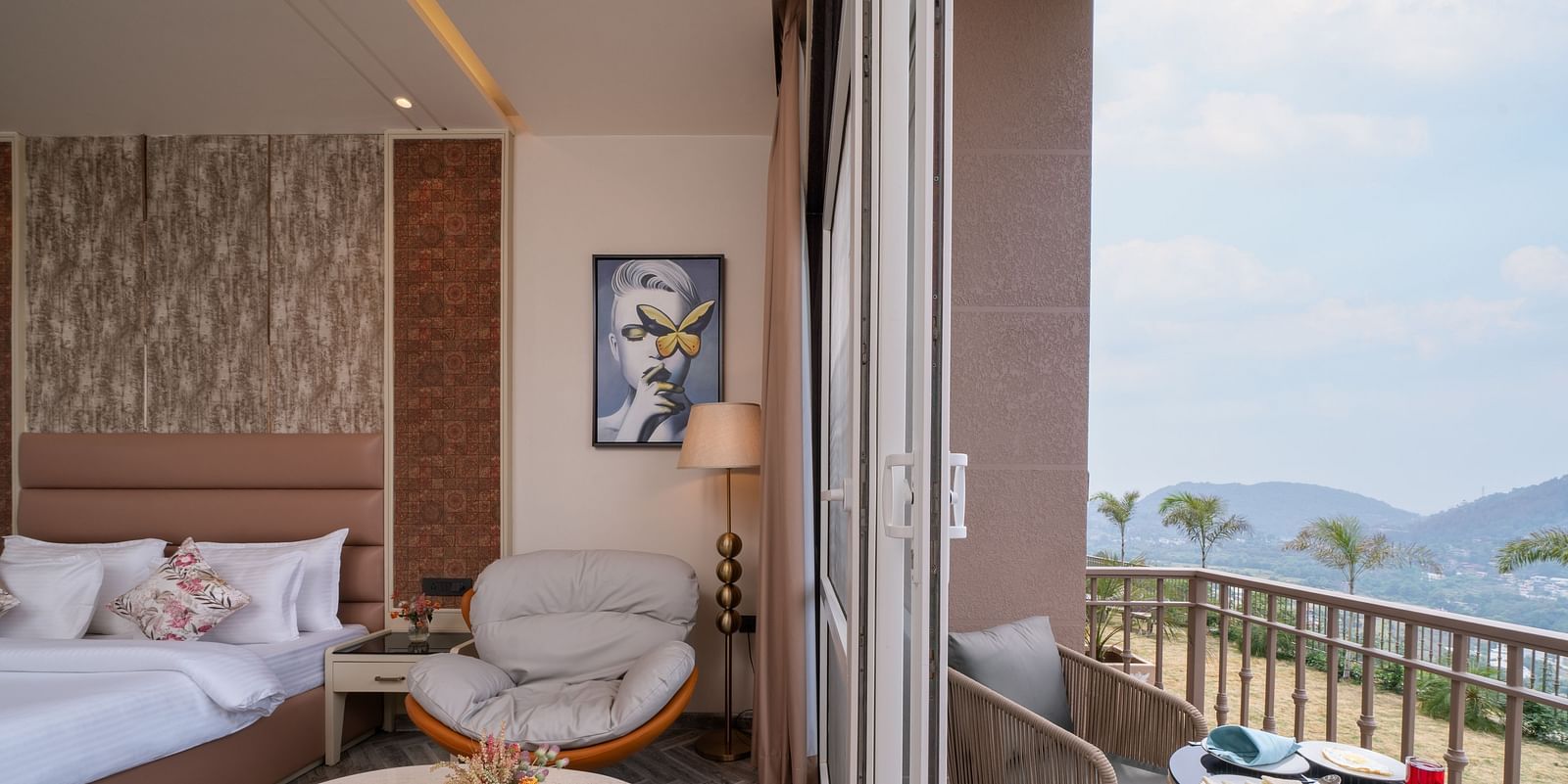 an image of a bedroom on one side with a single sofa and next to the room is a balcony with a seating arrangement -  Mountoria Retreat, Naukuchiatal