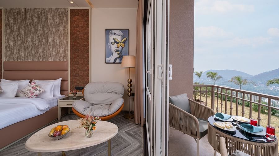 an image of a bedroom on one side with a single sofa and next to the room is a balcony with a seating arrangement -  Mountoria Retreat, Naukuchiatal